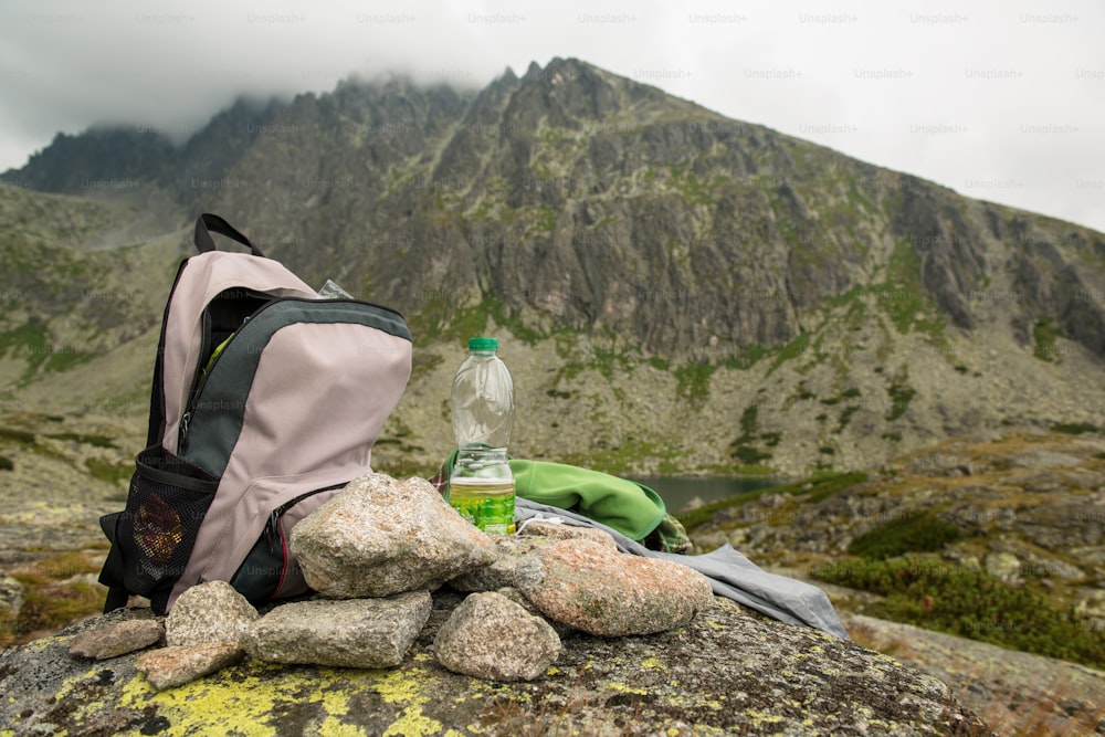 Stones, backpack and water bottle. Foggy and cloudy mountains after rain, rainy misty day, High Tatras Slovakia.  Beautiful mountain landscape.