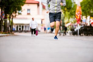 회색 스웨트셔츠를 입은 알아볼 수 없는 청년이 마을, 메인 스트리트에서 달리고 있다