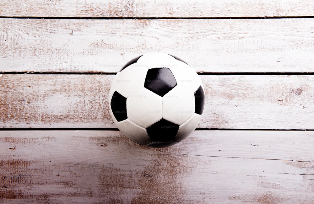 Ballon de football contre le plancher en bois, prise de vue en studio sur fond blanc. Espace de copie.