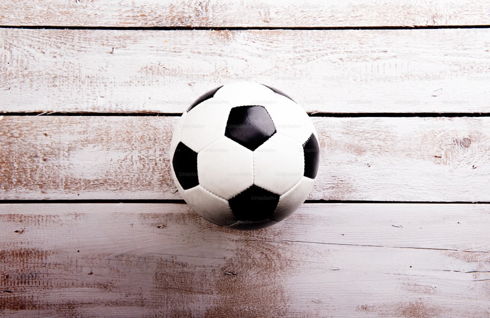 Soccer ball against wooden floor, studio shot on white background. Copy space.