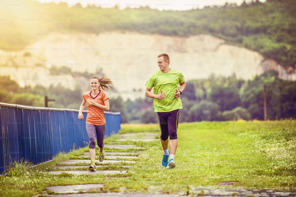 Young couple jogging on asphalt in rainy weather