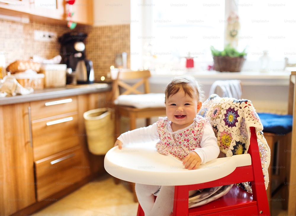 Feliz lindo bebé sentado en una silla alta en una cocina