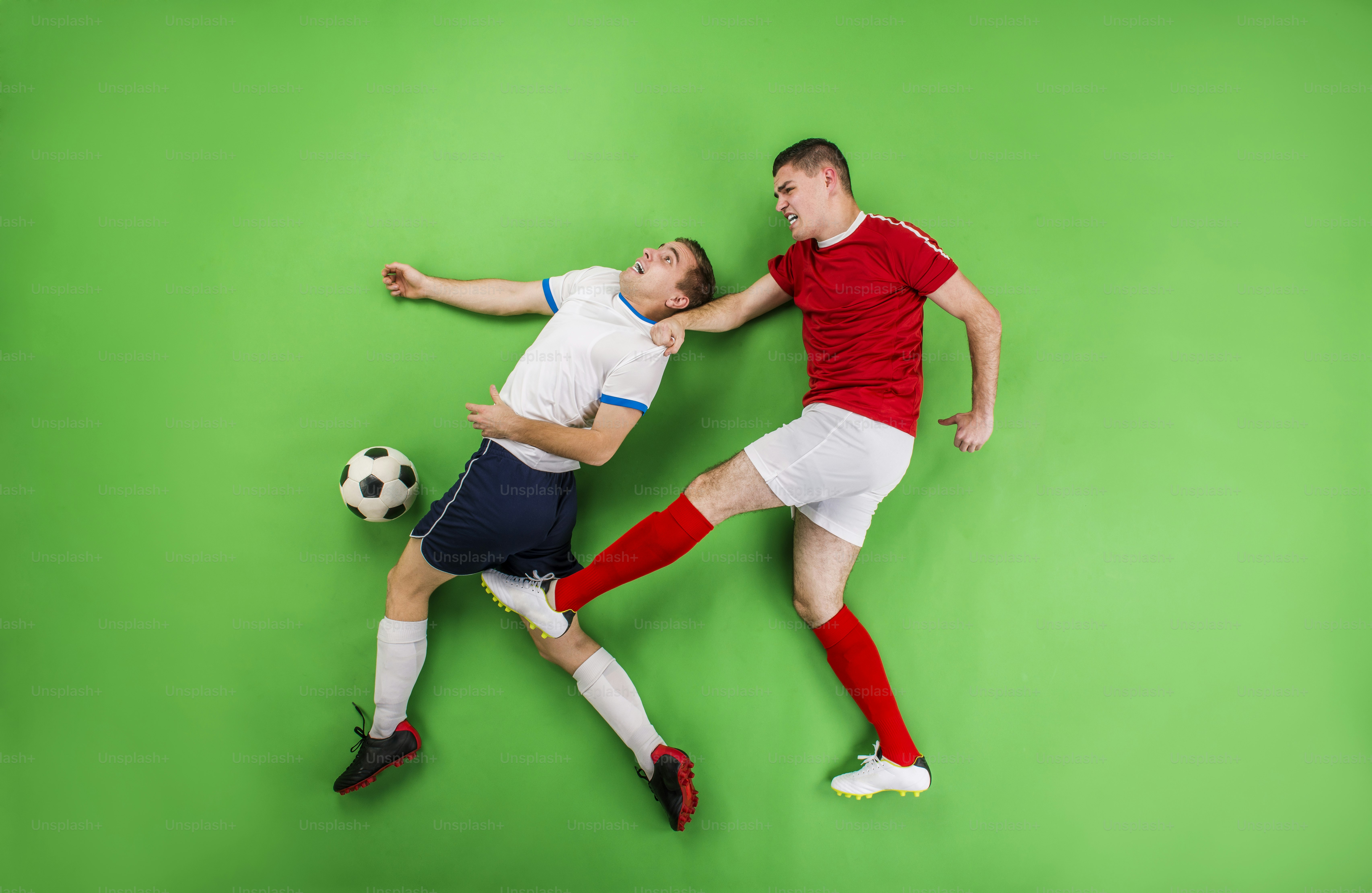 Dua pemain sepak bola bertarung untuk mendapatkan bola. Studio mengambil gambar di belakang hijau.