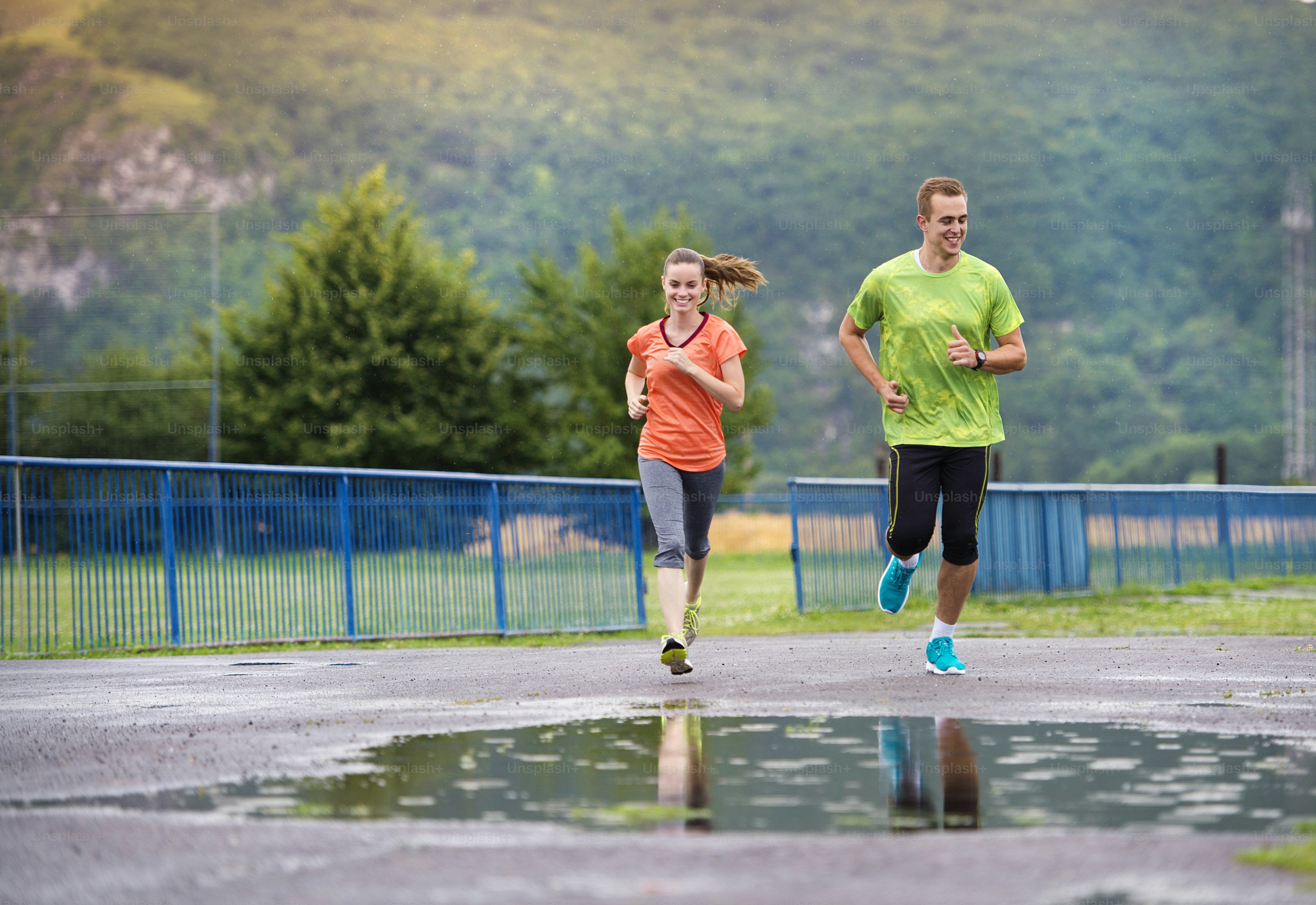 Young couple jogging on asphalt in rainy weather photo – Asphalt Image ...
