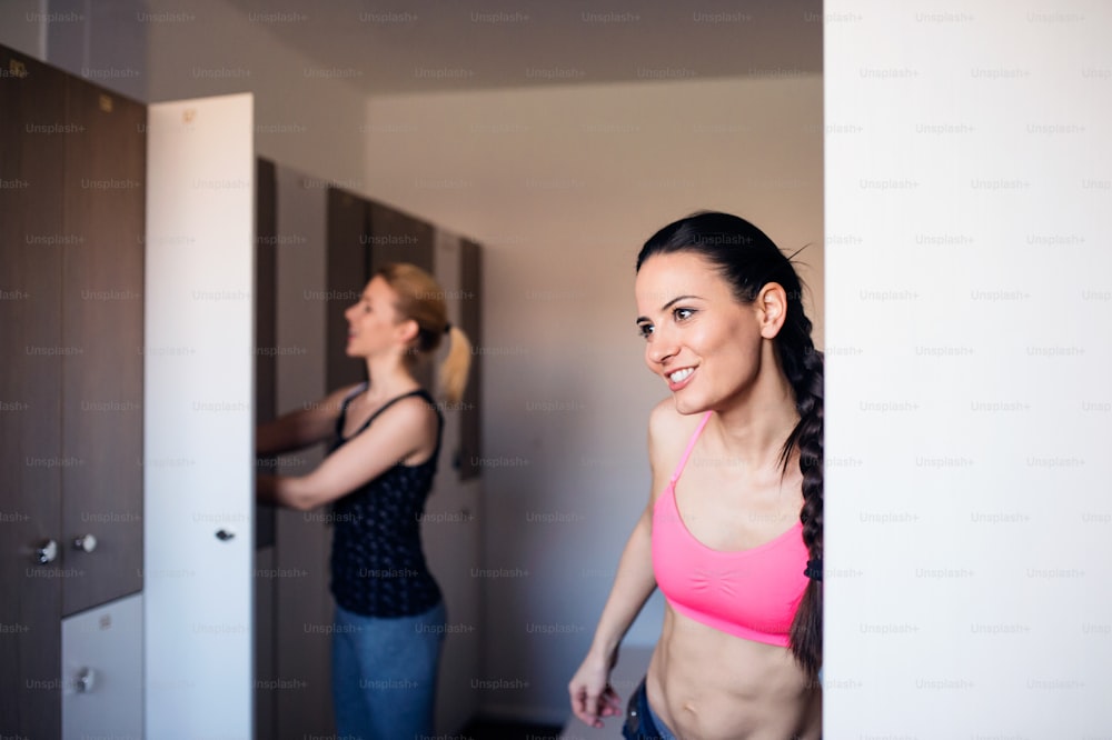 Zwei attraktive, fitte Frauen wechseln sich in der Umkleidekabine im Fitnessstudio um, Trainingskleidung