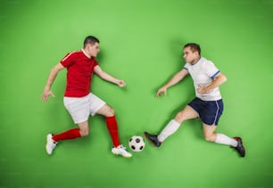 Dos jugadores de fútbol peleando por un balón. Estudio filmado sobre un fondo verde.