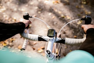 Sportivo irriconoscibile che guida la sua bicicletta all'aperto nella natura assolata di autunno, impostando il tachimetro