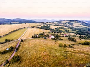 Vue aérienne de prairies verdoyantes, de maisons et de forêts, pendant une journée d’été ensoleillée. Slovaquie, Nova Bana.
