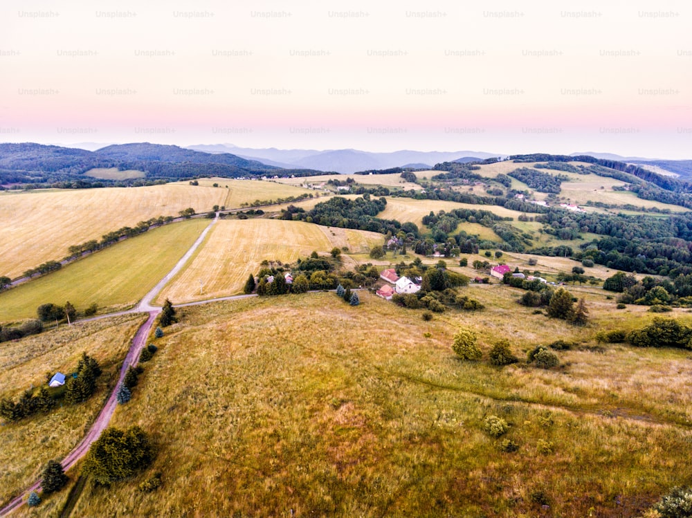 Vista aérea de verdes praderas, casas y bosques, durante un día soleado de verano. Eslovaquia, Nova Bana.