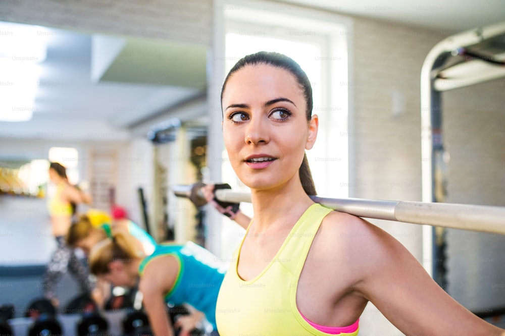 Close up de mulher atraente em forma no ginásio exercitando-se com pesos