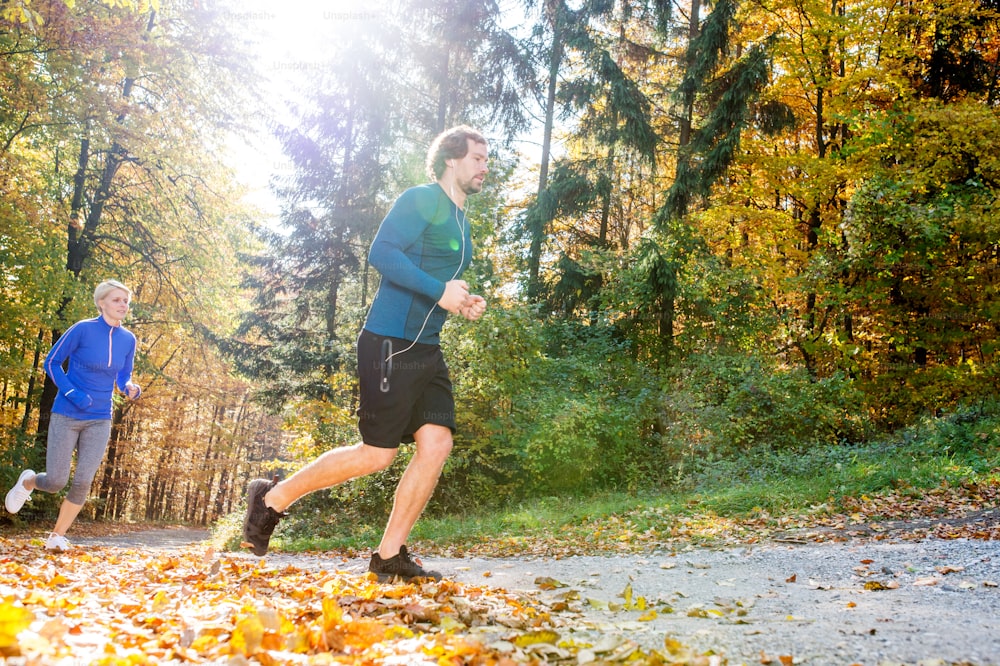 Beautiful couple running together outside in sunny autumn forest