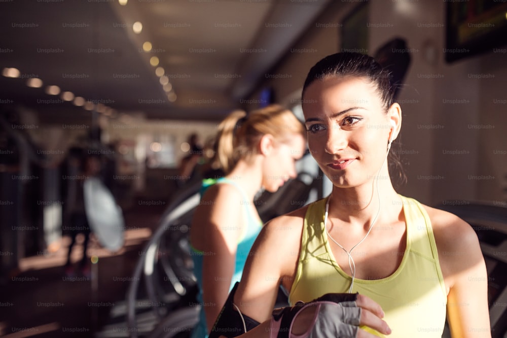 Close up of attractive fit woman in a gym after running on treadmill, sunny day
