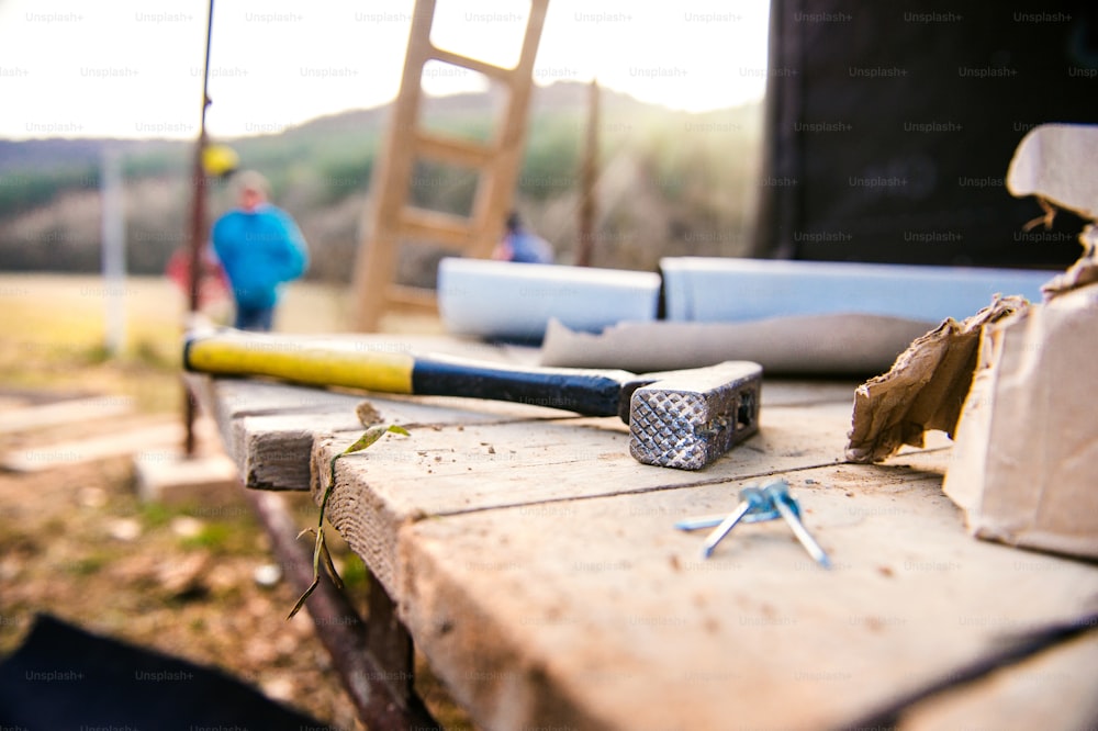 Close up do martelo com pregos em placas de madeira do lado de fora no canteiro de obras