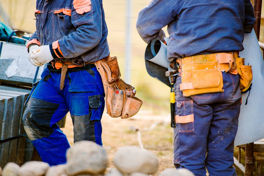 Close up of two construction workers with tool bags on site