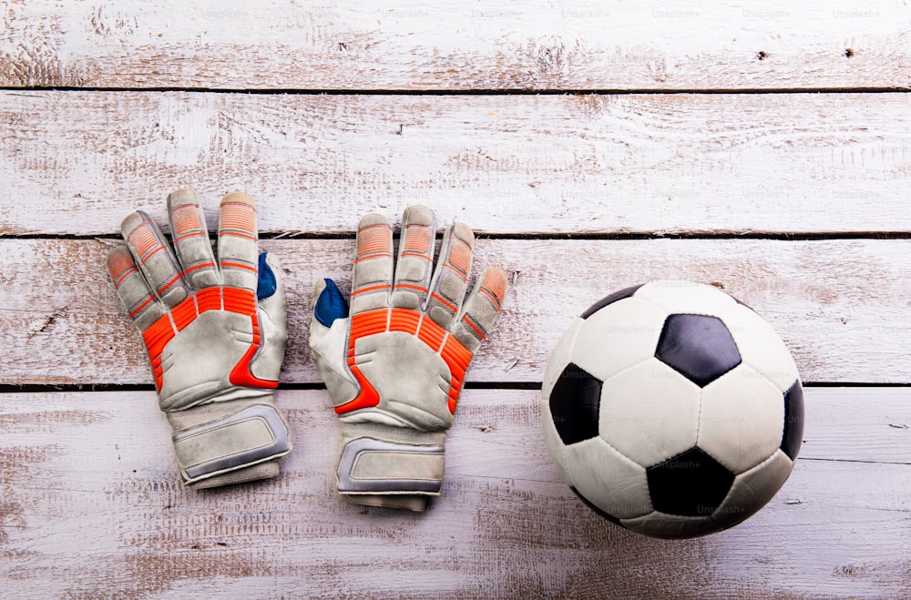 Soccer ball, gloves against wooden floor, studio shot on white background. Flat lay, copy space