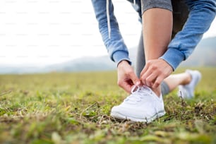 Close up of an unrecognizable young runner tying shoelaces, autumn nature