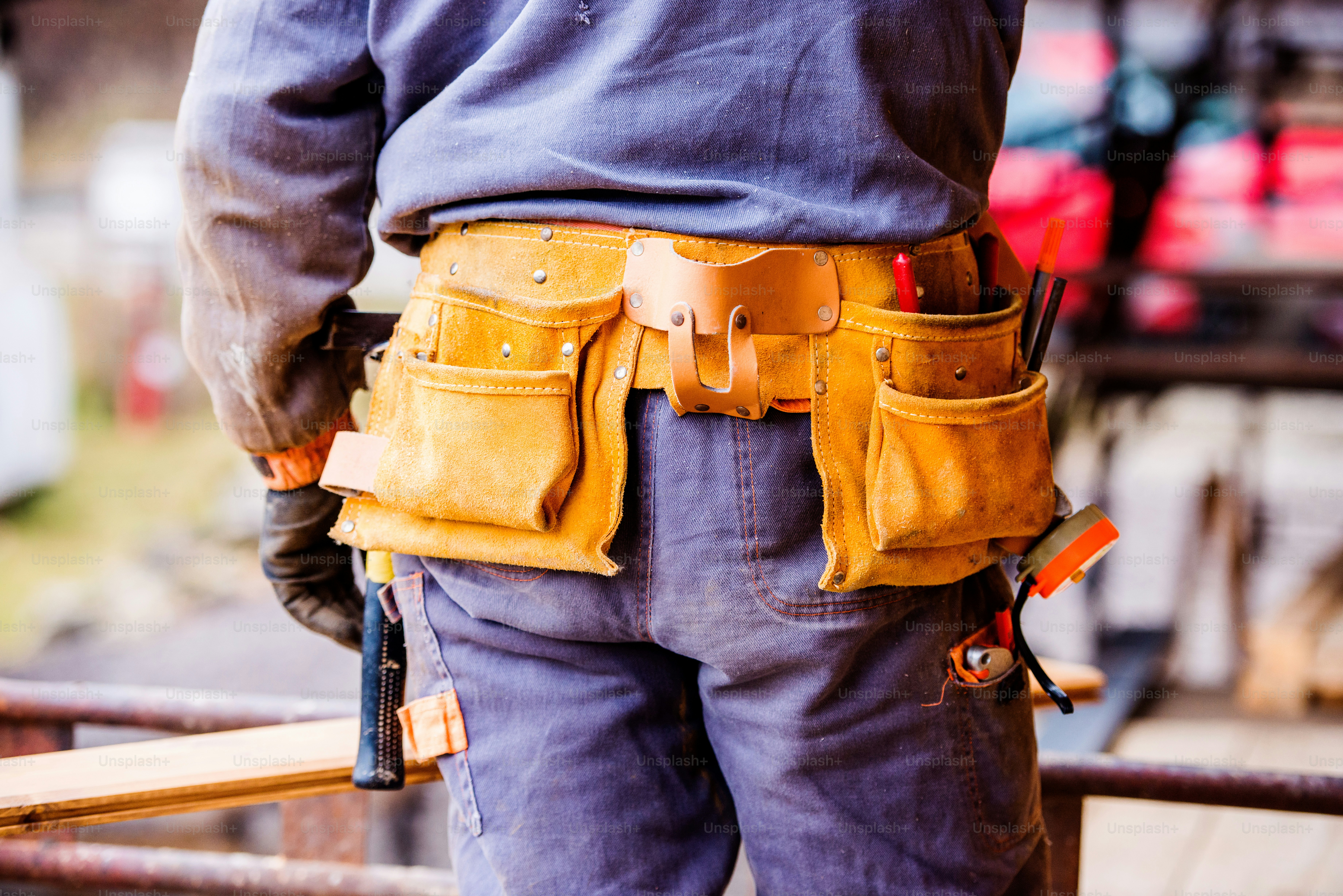 Rear view of a worker with a canvas tool bag on a site