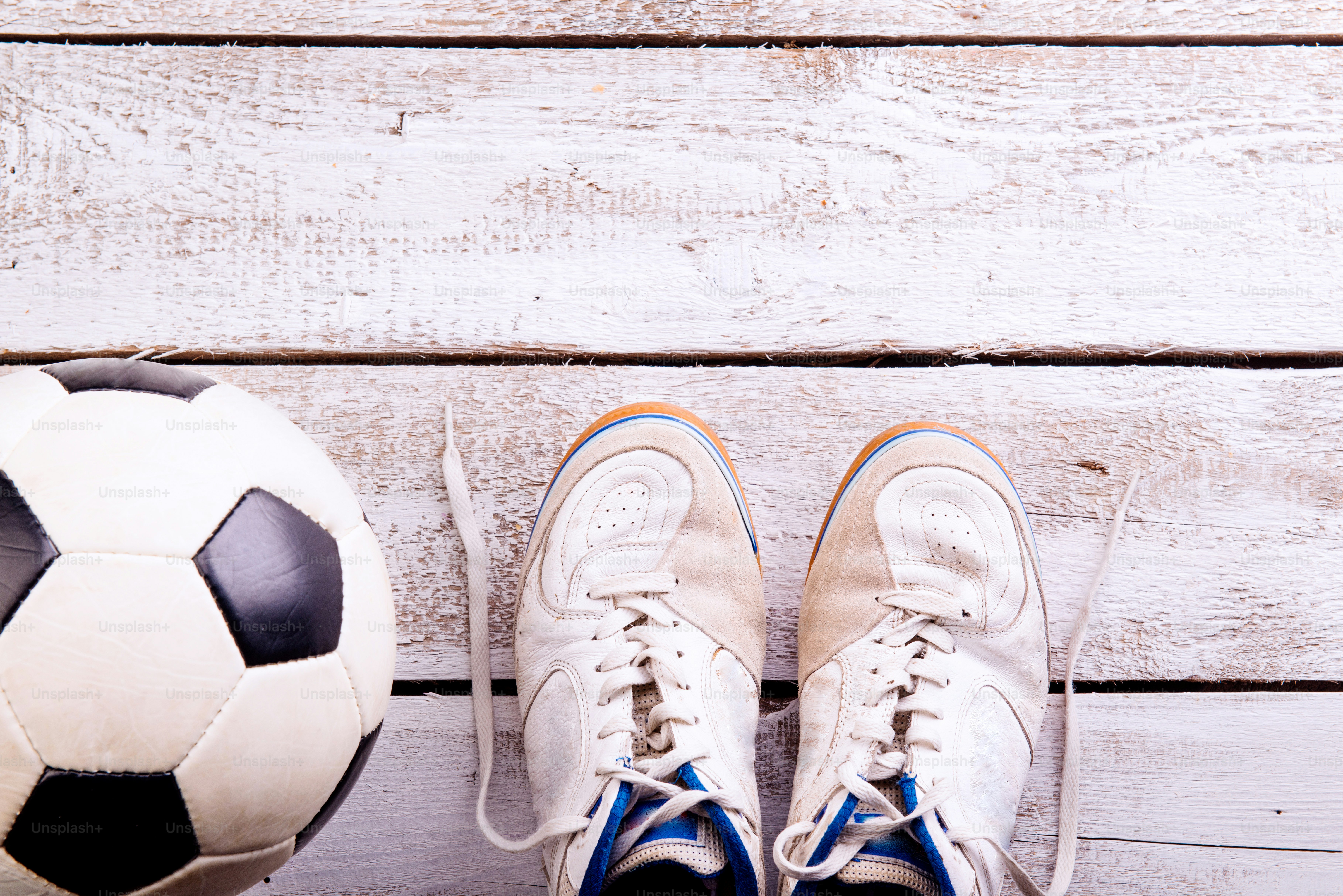 Soccer ball, cleats against wooden floor, studio shot on white background. Flat lay, copy space