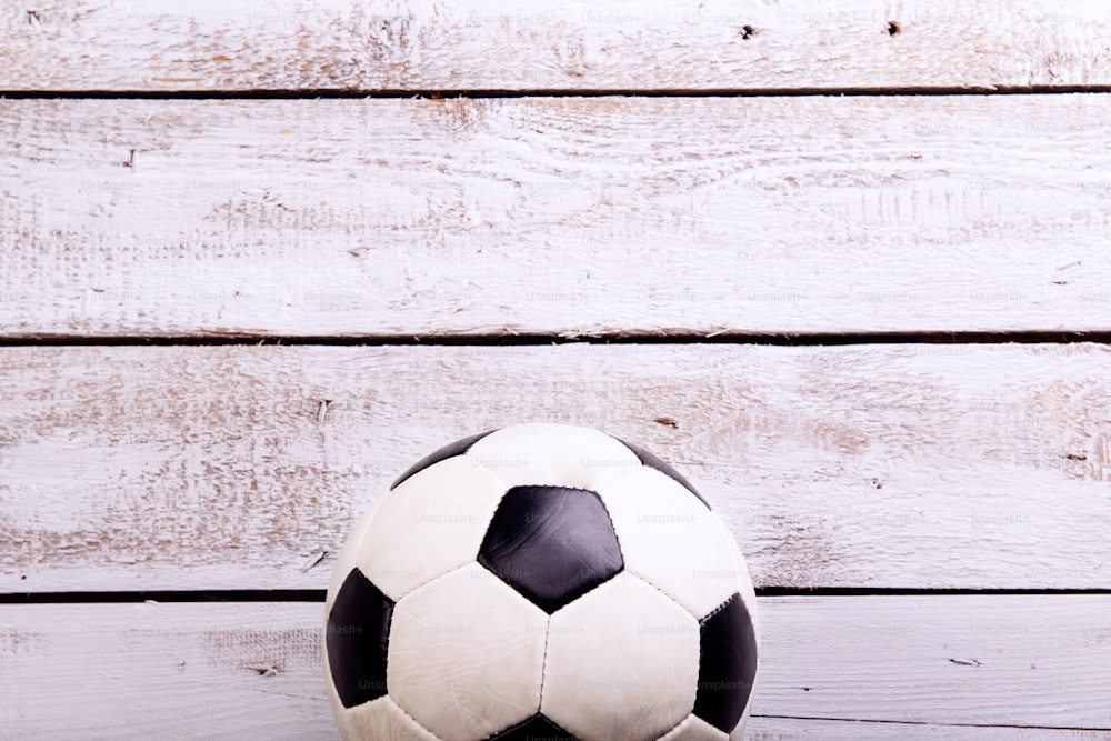 Soccer ball against wooden floor, studio shot on white background. Copy space.