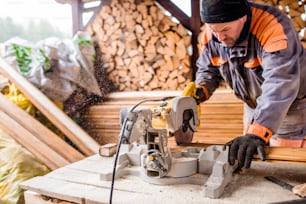 Carpenter working. Man using circular saw to cut planks of wood for home construction