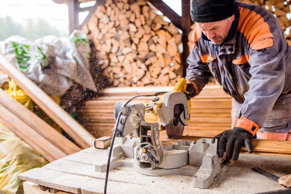 Carpinteiro trabalhando. Homem usando serra circular para cortar tábuas de madeira para a construção de casas