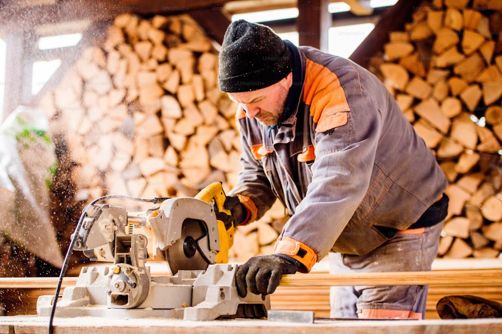 Carpinteiro trabalhando. Homem usando serra circular para cortar tábuas de madeira para a construção de casas