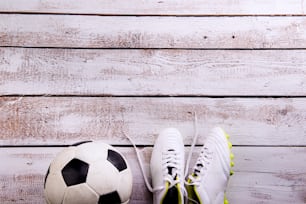 Soccer ball, cleats against wooden floor, studio shot on white background. Flat lay, copy space