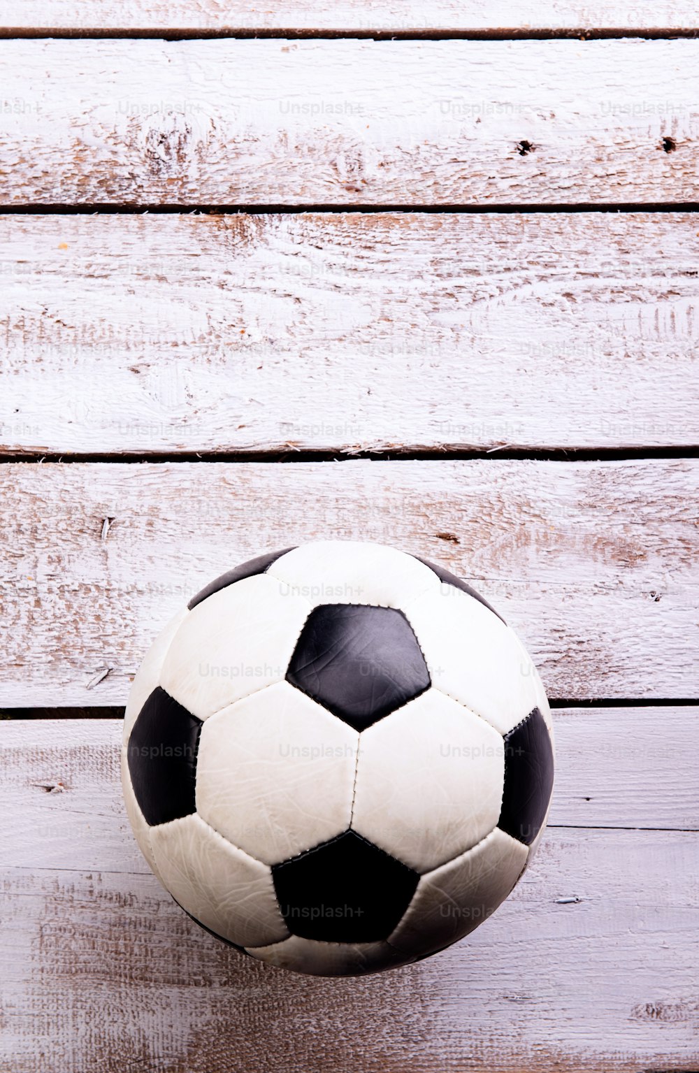 Soccer ball against wooden floor, studio shot on white background. Copy space.