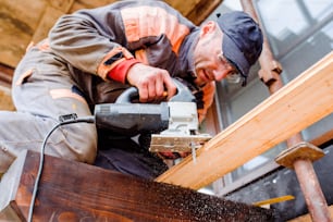 Carpintero con amoladora. Hombre moliendo tablones de madera para la construcción de casas.