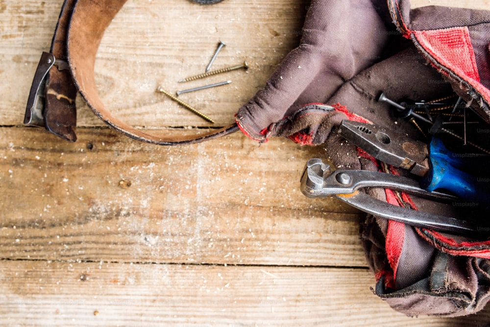 Carpenters bag with belt full of tools laid on table. Studio shot on wooden background. Copy space.