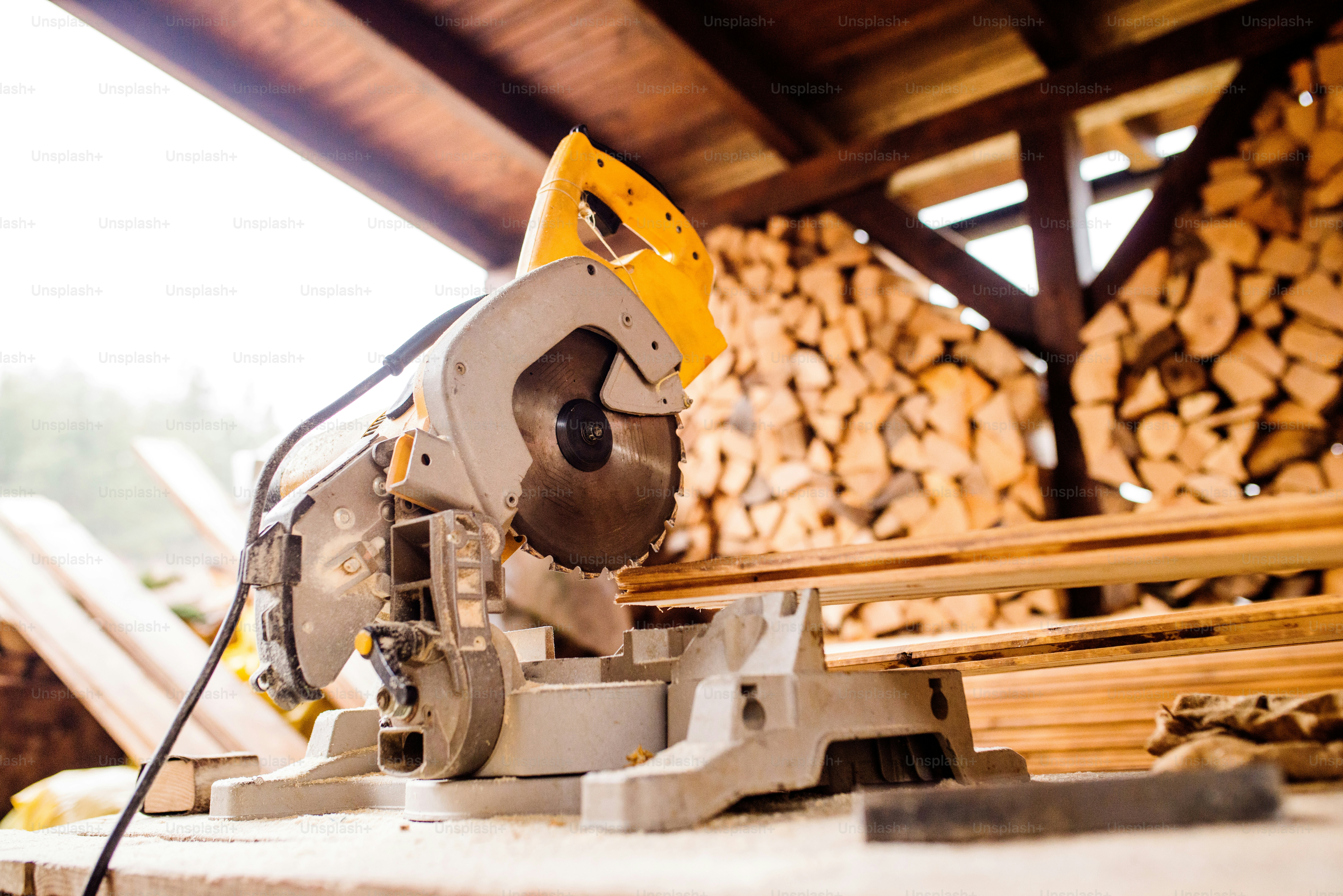 Close up of circular saw laid on table, stack of wood behind it photo ...
