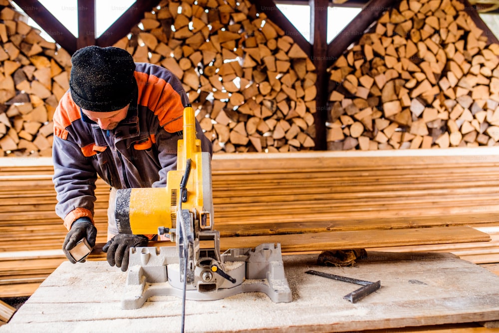 목수 작업. 원형 톱을 사용하여 주택 건설을 위한 나무 판자를 자르는 남자