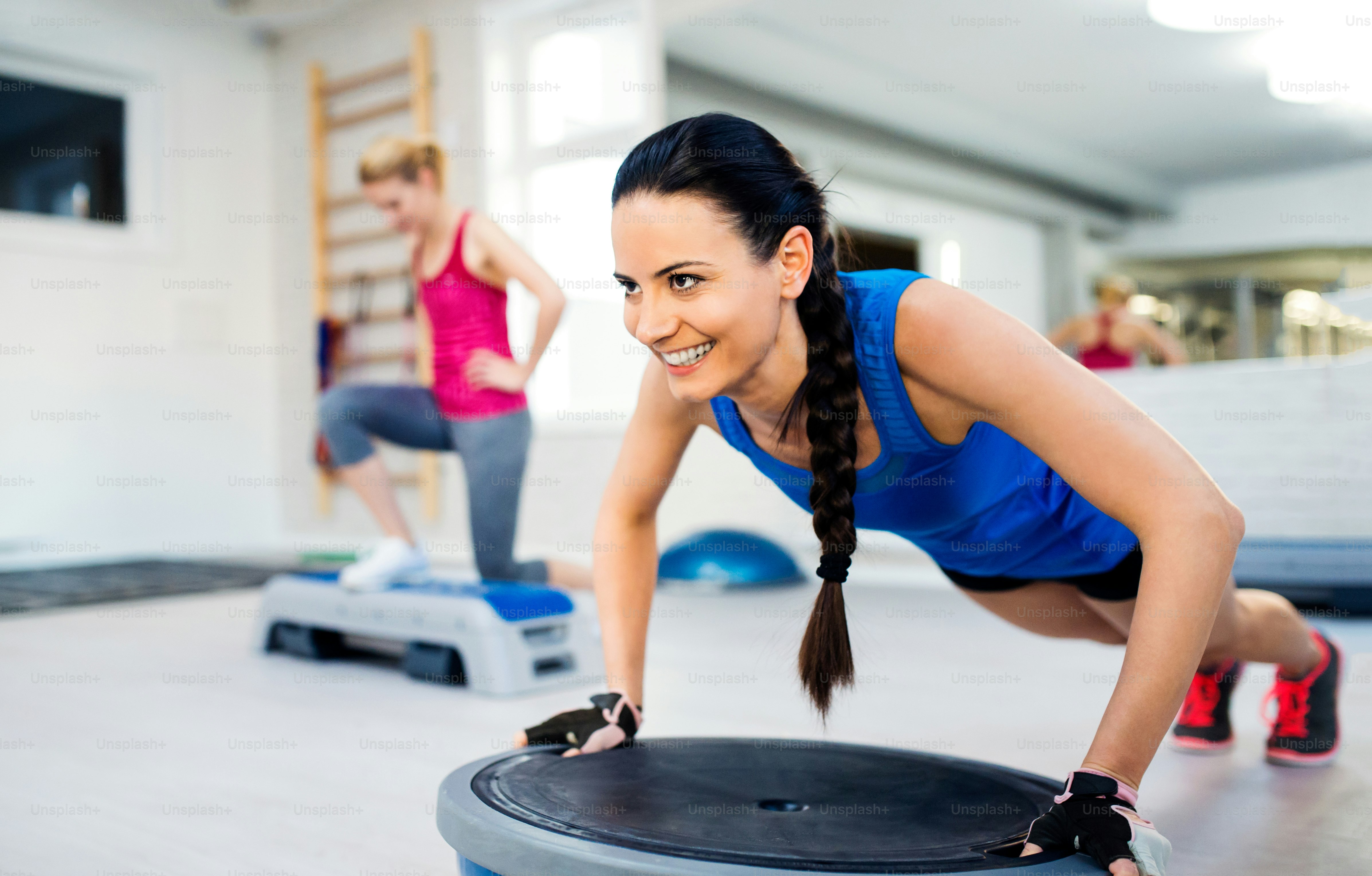 Dua wanita muda yang bugar di gym melakukan berbagai latihan
