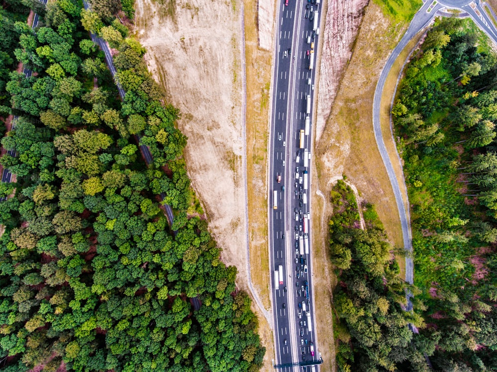 Aerial view of highway full of cars and trucks, traffic jam in the middle of green forest, Netherlands