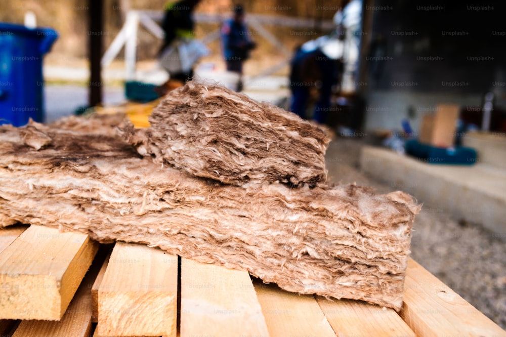 Morceaux de laine d'isolation de verre portant sur des poutres en bois portant sur le chantier de construction