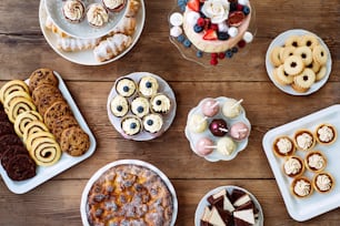 Tisch mit Kuchen, Torte, Cupcakes, Keksen, Torten und Kuchen. Studioaufnahme auf braunem Holzhintergrund. Flache Liege.