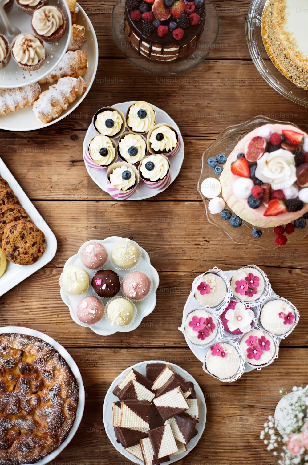 Table with loads of cakes, cupcakes, cookies, pie and cakepops. Studio shot on brown wooden background. Flat lay.