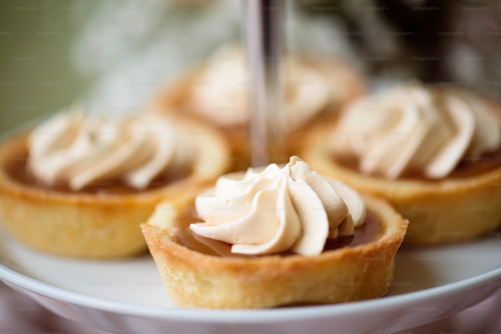 Close up, tarts filled with jam decorated with vanilla cream laid on cakestand. Studio shot.