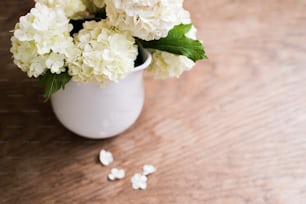 Hermoso ramo de lilas en jarrón colocado sobre la mesa. Estudio de estudio sobre fondo blanco de madera. Espacio de copia.