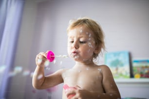 Menina pequena de dois anos de idade em casa doente com varicela, creme antisséptico branco aplicado à erupção cutânea