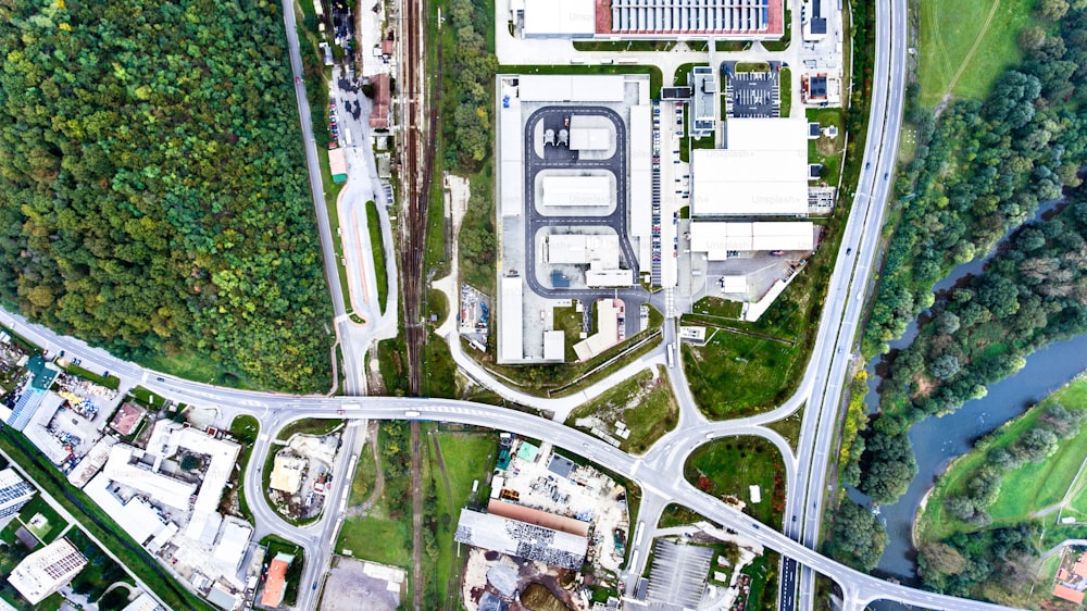 Vista aérea de edifícios industriais, rodovia e pequena cidade de Nova Bana, na Eslováquia, cercada por natureza verde.