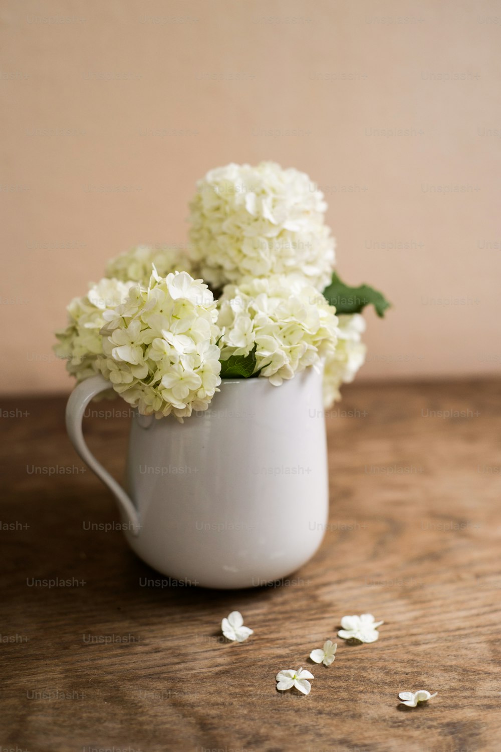 Beautiful white lilac bouquet in vase laid on table. Studio shot on wooden background. Copy space.