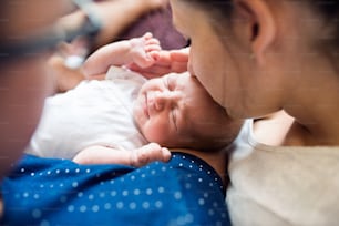 Unrecognizable father and mother holding their newborn baby boy in the arms, mom kissing her son