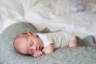 Cute little newborn baby boy lying on bed, sleeping, close up