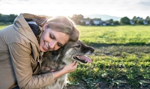 Beautiful young woman on a walk with a dog in green sunny nature