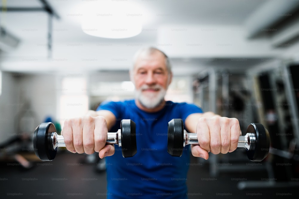 Uomo anziano in abbigliamento sportivo in palestra che si allena con i pesi. Primo piano delle mani.