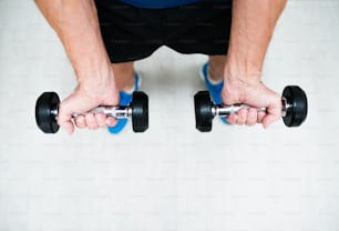 Primer plano de las manos de un hombre mayor en el gimnasio que hace ejercicio con pesas