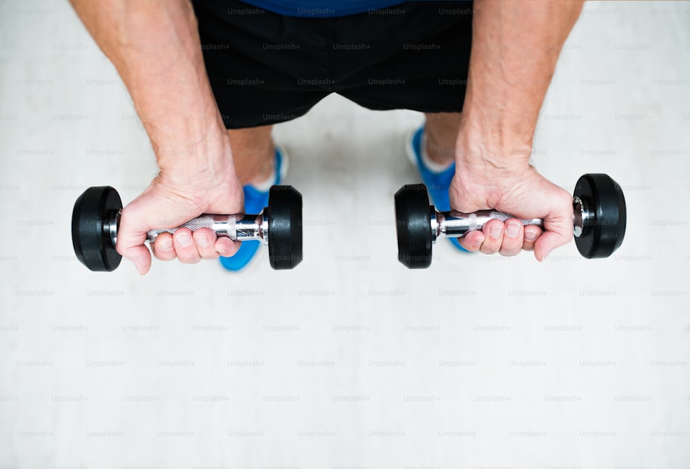 Nahaufnahme der Hände eines älteren Mannes im Fitnessstudio beim Training mit Gewichten
