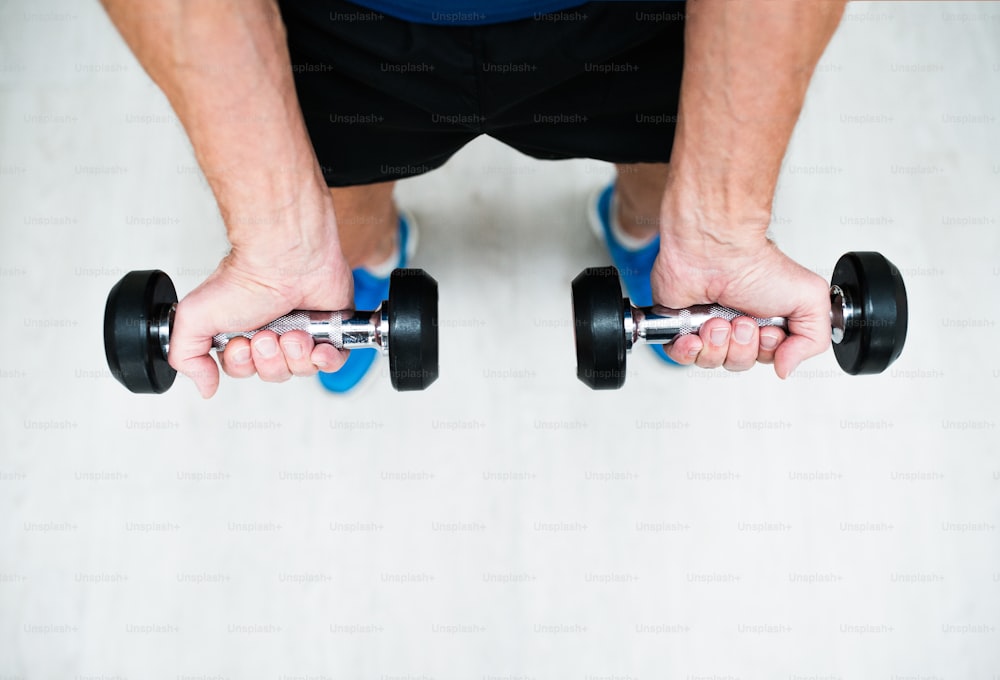 Close up of hands of senior man in gym working out with weights