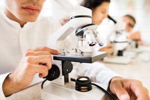 Studenti delle scuole superiori irriconoscibili con microscopi in laboratorio durante la lezione di biologia.